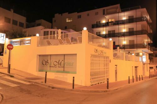 a white building on a street at night at Es Mitjorn Hotel in San Antonio
