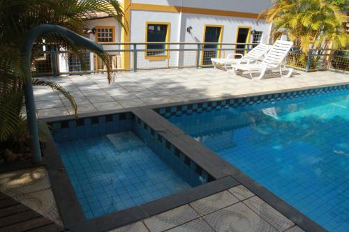 a swimming pool with two chairs and a swimming pool at Pousada do Canto in Rio Acima