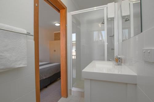 a white bathroom with a sink and a shower at River Street Motel in Ballina