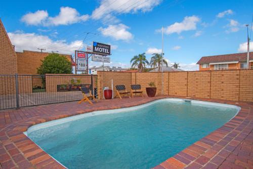 a swimming pool with a brick fence and a building at River Street Motel in Ballina