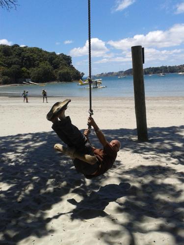 a man on a swing on the beach at Jake's Place Oneroa Waiheke in Oneroa