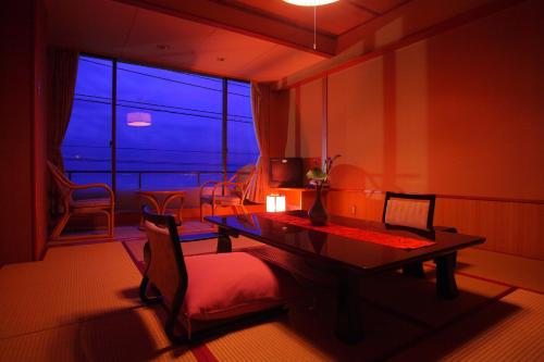 a room with a table and chairs and a large window at Hiina in Higashiizu