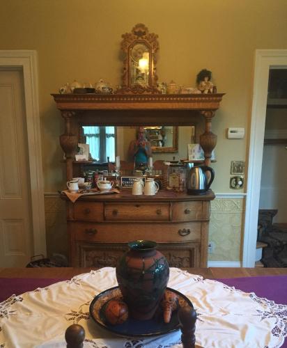 a wooden dresser with a mirror and a vase on a bed at The Whitmore Inn in Weaverville