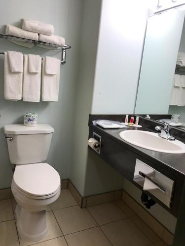 a bathroom with a toilet and a sink and a mirror at Super 8 by Wyndham Kindersley in Kindersley