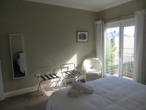 a bedroom with a bed and two chairs and a balcony at Northwood Bed and Breakfast in Perth