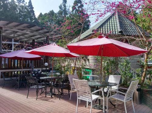a patio with tables and chairs with red umbrellas at Gemlu in Lugu
