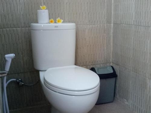 un inodoro blanco con un rollo de papel higiénico encima en Minory Guesthouse, en Amed