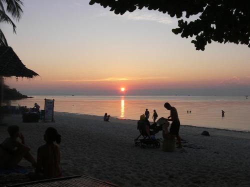 a group of people on the beach at sunset at Ibiza Bungalows in Haad Yao