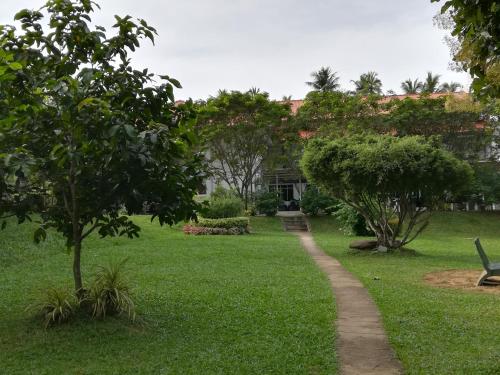 a path through a park with trees and a building at Grindlays Regency in Ambepussa