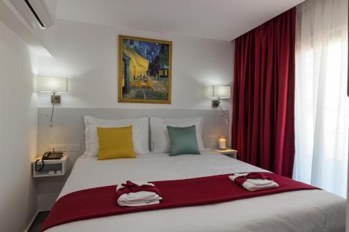a bedroom with a large white bed with red curtains at Art & Wine Boutique Hotel in Larnaka
