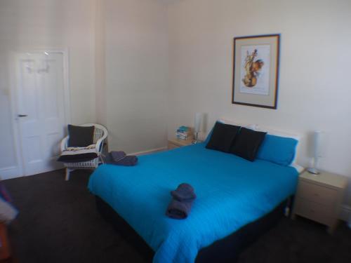 a bedroom with a blue bed with a hat on it at Windsor Cottage in Kingston Beach