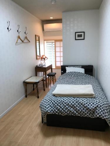 a bedroom with a bed and a table and a desk at Ryokan Seifuso in Ōmuta