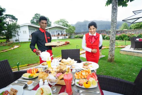 a man and a woman standing next to a table with food at La Grande Villa in Nuwara Eliya
