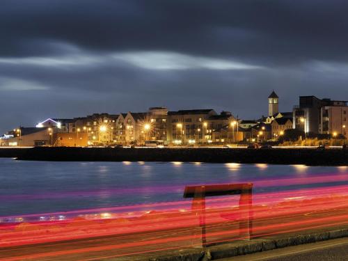 a red bench sitting next to a body of water at night at HYDE Hotel in Galway