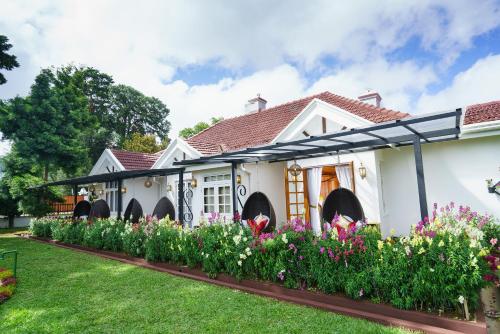 a house with a garden with flowers in the yard at La Grande Villa in Nuwara Eliya