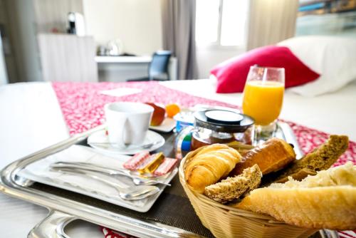 a tray with a basket of bread and a glass of orange juice at Hôtel Saphir Lyon in Lyon