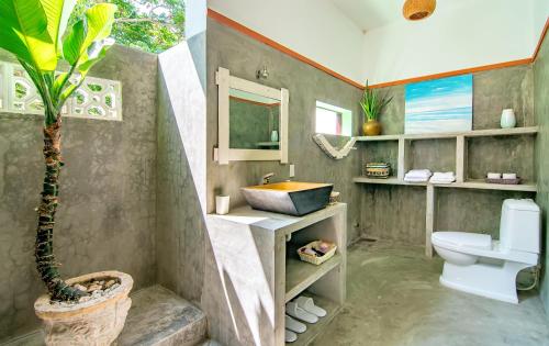 a bathroom with a sink and a toilet and a plant at An Bang Flower House in Hoi An