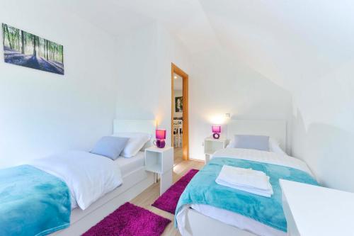a white bedroom with two beds and a mirror at Apartments Relax in Saborsko