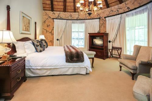 a bedroom with a bed and a couch and a chair at Summerfield Botanical Garden & Exclusive Resort in Matsapha