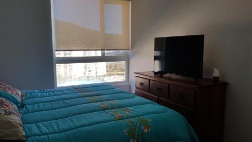 a bedroom with a bed and a television on a dresser at Papudo Laguna in Papudo