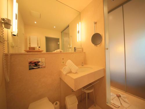 a bathroom with a sink and a toilet and a mirror at Bio Thermalhotel Falkenhof in Bad Füssing