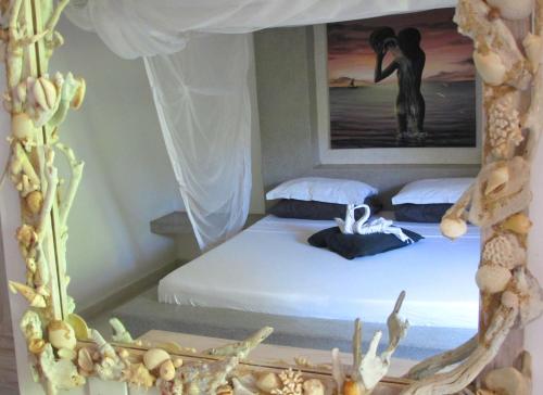 a bedroom with a bed with a painting on the wall at Baobab Village in Watamu