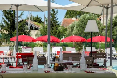 a group of tables and chairs with red umbrellas at ibis Orange Centre in Orange