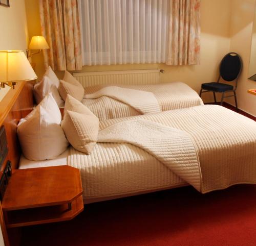 a bedroom with a bed with white sheets and pillows at Brocki's Hotel Stadt Hamburg in Parchim