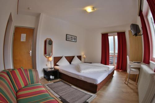 een slaapkamer met een bed, een bank en een stoel bij Alpenhotel in Oetz