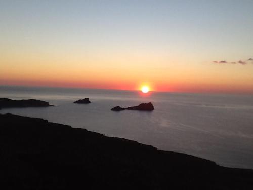 a sunset over the ocean with rocks in the water at Liviko View in Xerokampos