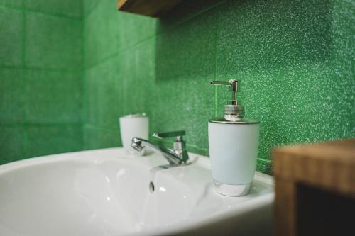 a bathroom sink with a faucet and a green wall at Surfpoint Sri Lanka Kite Village in Kalpitiya