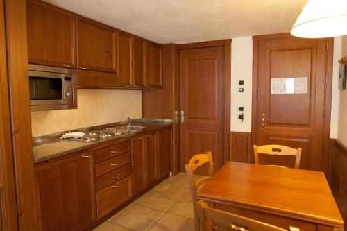 a kitchen with wooden cabinets and a wooden table at Residence Le Grand Chalet in Courmayeur