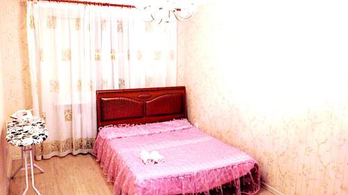 um quarto com uma cama com lençóis cor-de-rosa e uma janela em Apartment in heart of Astana em Astana