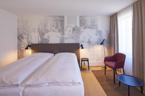 a bedroom with a large white bed and a red chair at Hotel Gasthof zum Ochsen in Arlesheim