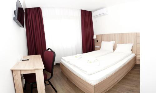 a bedroom with a bed and a table and a desk at Pensiunea Otopeni in Otopeni