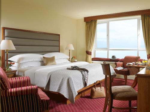 een hotelkamer met een bed en twee stoelen bij Galway Bay Hotel Conference & Leisure Centre in Galway