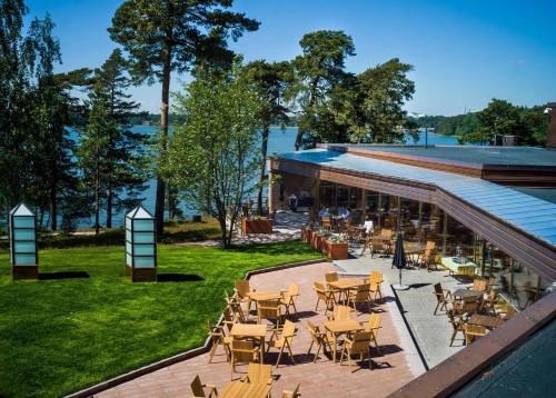 an outdoor patio with tables and chairs and the water at Hotel Hanasaari in Espoo