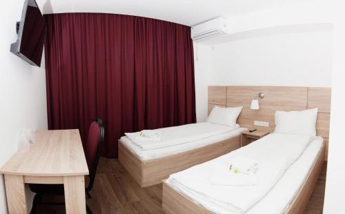 a hotel room with two beds and a table at Pensiunea Otopeni in Otopeni