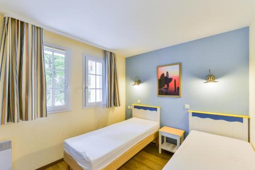 フエナンにあるResidence Cap Azur - maeva Homeのベッド2台と窓2つが備わる客室です。