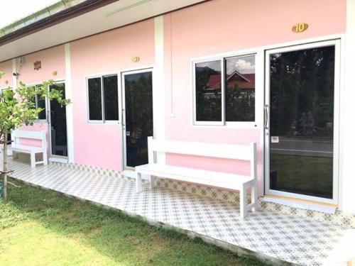 a pink house with two benches outside of it at Baan Suan Kru Kob in Ban Ko Maphang