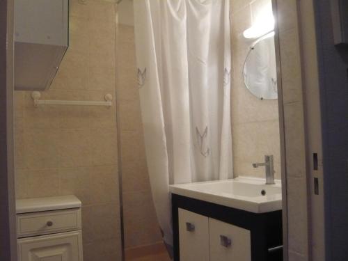 une salle de bain avec un rideau de douche et un lavabo dans l'établissement Appartement à Carqueiranne, à Carqueiranne