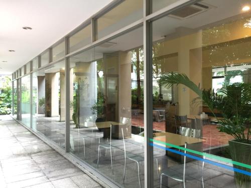 a lobby with glass walls and tables and plants at Rio Monte Residence in Bangkok