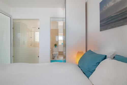 - une chambre avec un lit blanc et des oreillers bleus dans l'établissement Dream On the Beach, à Haïfa