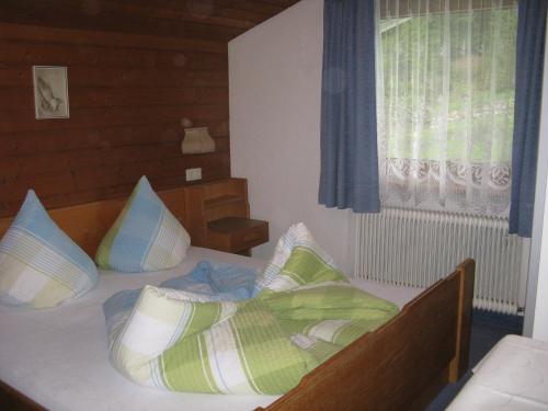 una camera da letto con letto, cuscini e finestra di Ferienwohnung Wohlfarter a Jerzens