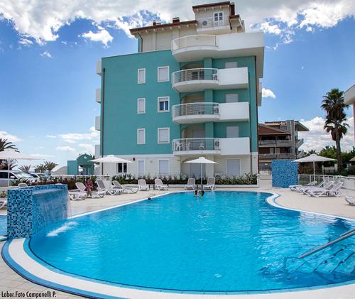 a hotel with a large swimming pool in front of a building at Residence Acquasuite in Martinsicuro