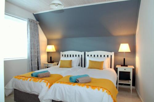 Charming Fisante house في هيرمانوس: غرفة نوم بسريرين بملاءات صفراء وبيضاء