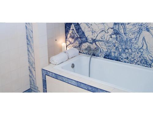 un bagno con vasca e un dipinto sul muro di A Pausa ad Alvor