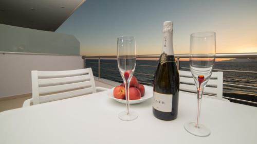 a bottle of wine and two glasses on a table at Bella Mare Luxury Apartments in Kalamaki Heraklion