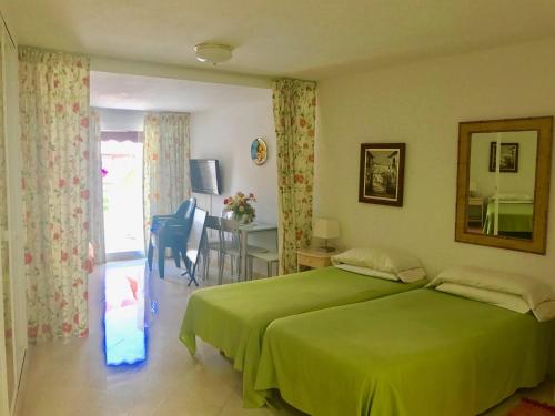 a bedroom with a green bed and a dining room at Parque Marbella in Marbella