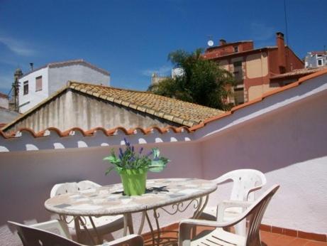 una mesa con sillas y un jarrón de flores en el balcón en Apartamentos Mitus, en Canet de Mar